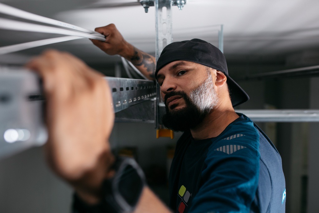 Monteur verlegt Kabel auf einer Kabeltrasse